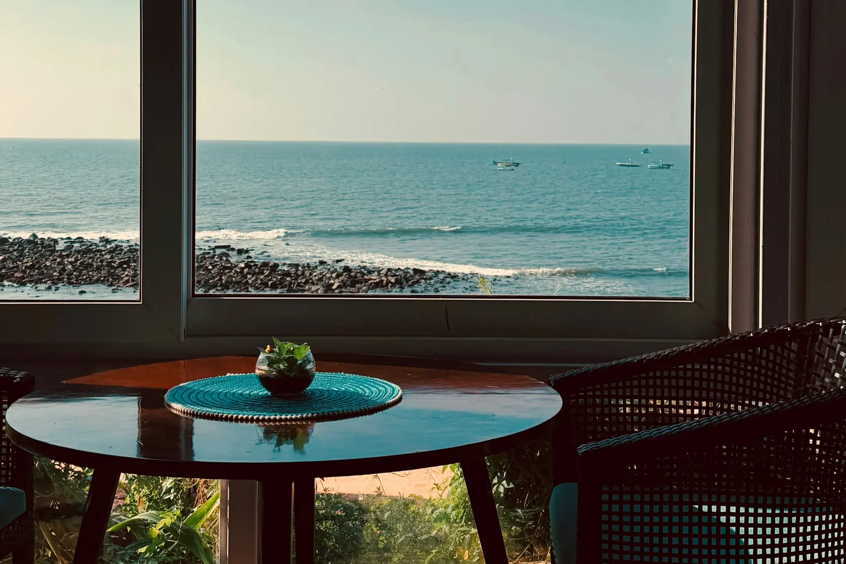 A table by a window with the ocean beyond it